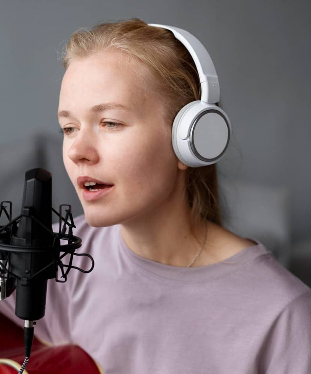 Teen girl singing into microphone wearing white headphones