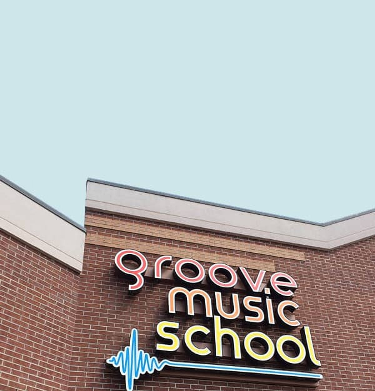 Groove Music School sign on brick building against sky