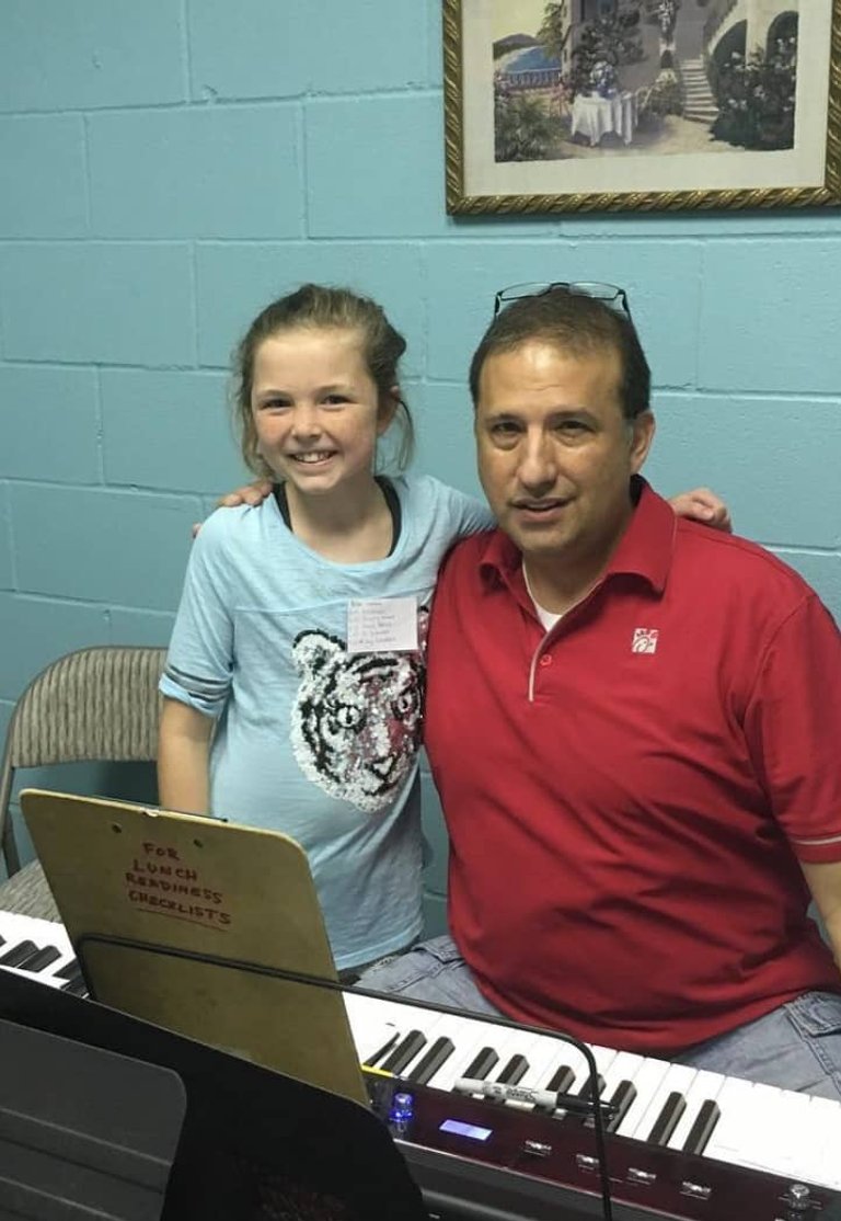 Girl and instructor pose with keyboard during music lesson