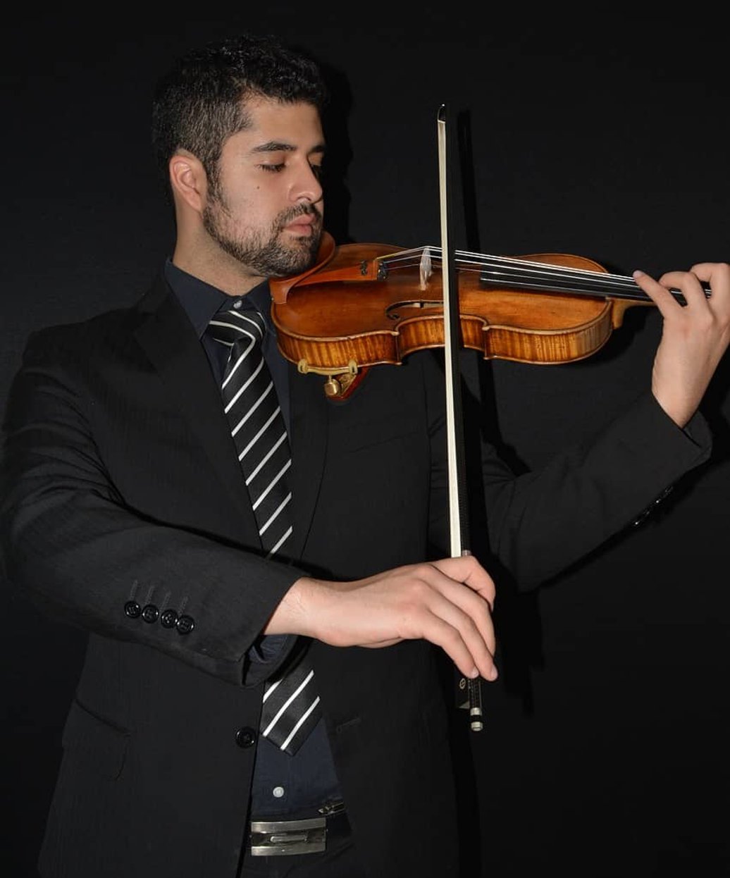 Man in suit playing violin against black background