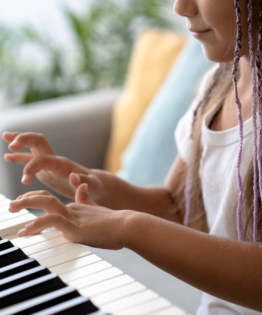 Girl with braids playing piano keys at home