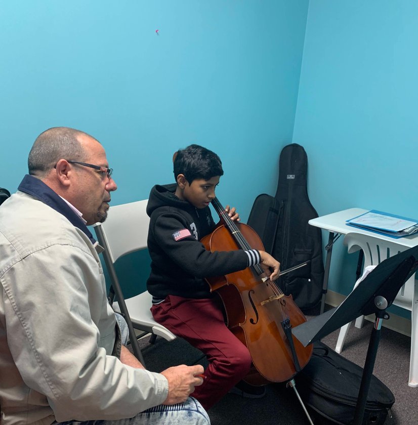 Instructor teaching boy cello technique during one-on-one lesson in practice room
