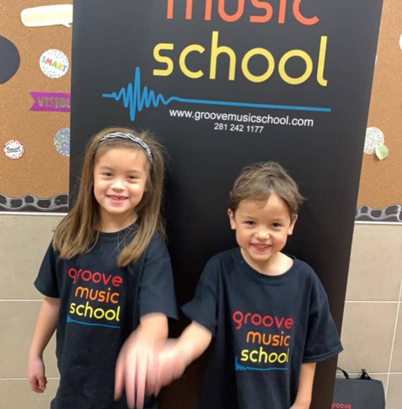 Two kids in matching Groove Music School shirts smiling