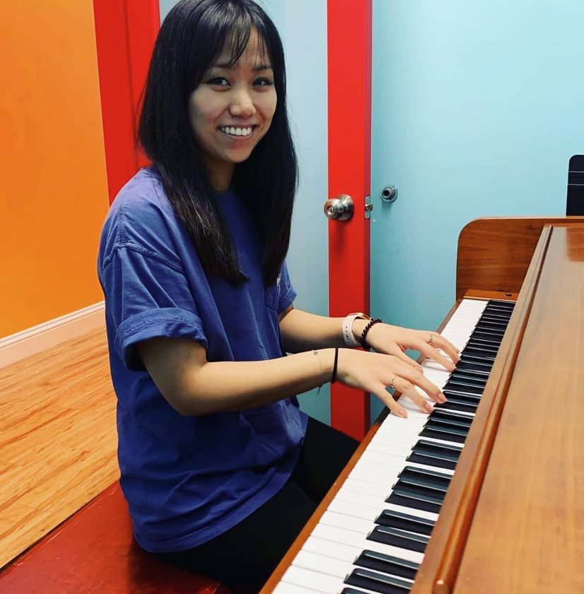Young woman smiling while playing piano in colorful room