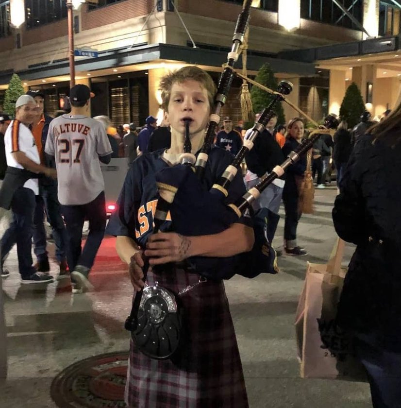 Boy playing bagpipes outdoors in kilt at night event