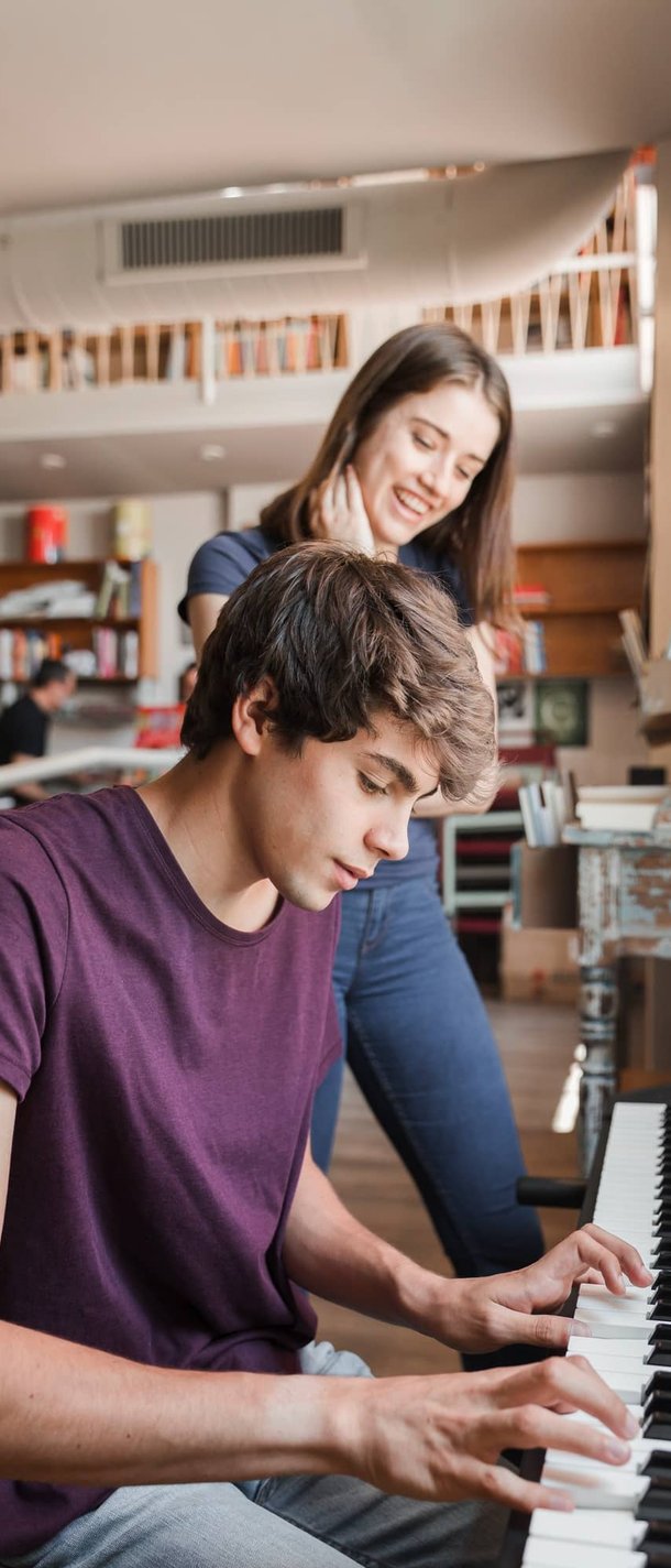Woman watching teen boy play piano in home